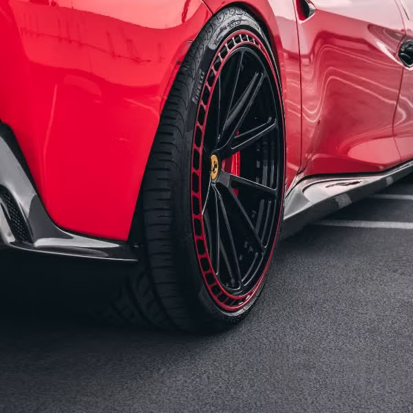 Close-up of clear paint protection film wrapped over the lower body and arches of a red Ferrari by Monarch