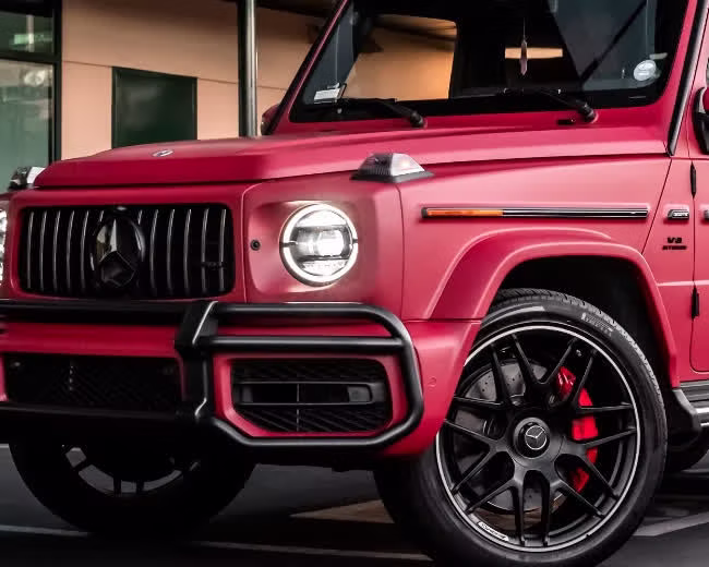 Close-up of the matte red metallic finish, grille and wheel on a Mercedes-AMG G63 wrapped by Monarch